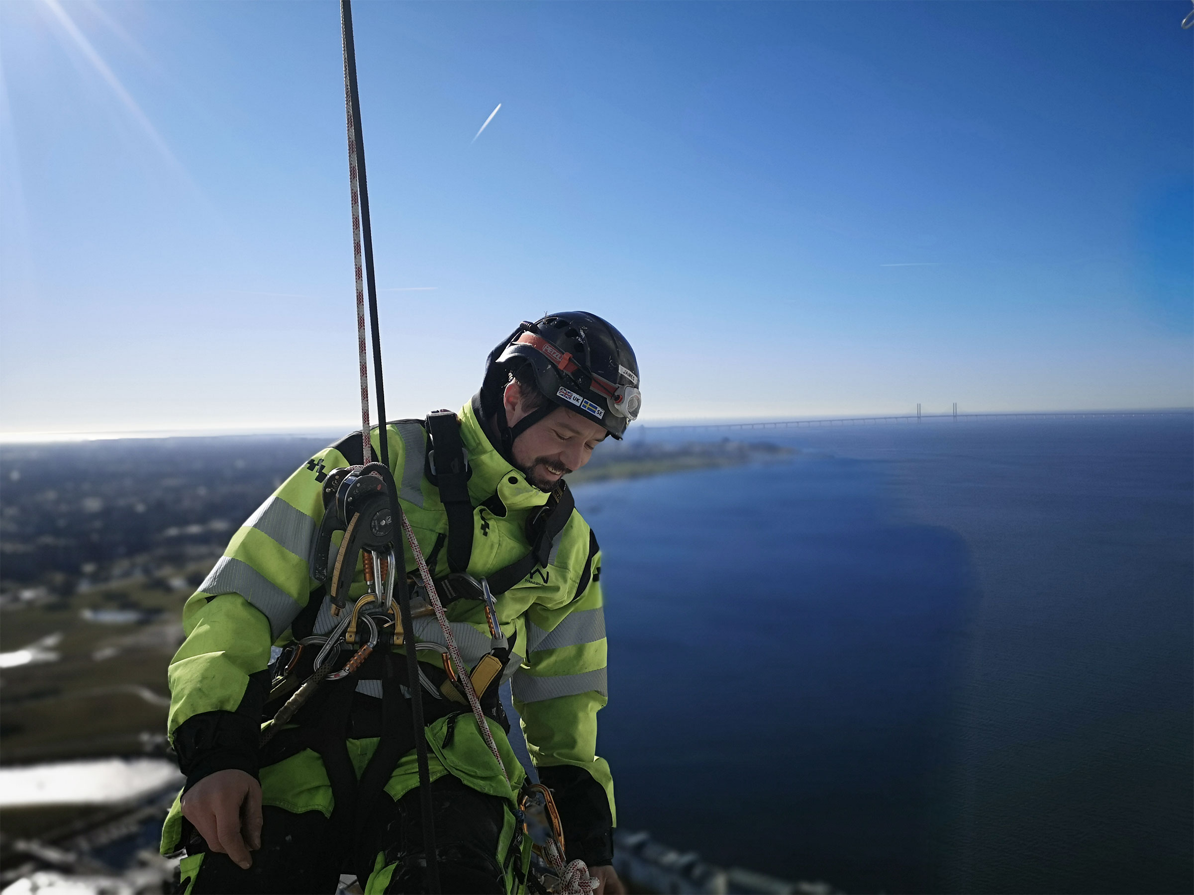 man hängandes i sele från skyskrapa med utsikt över öresund