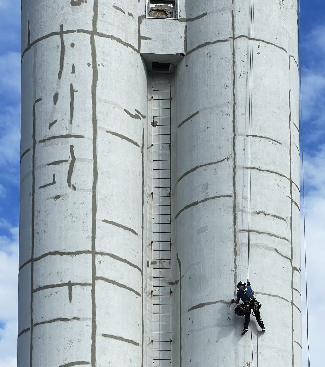 Man hängandes i sele och arbetar på fasad