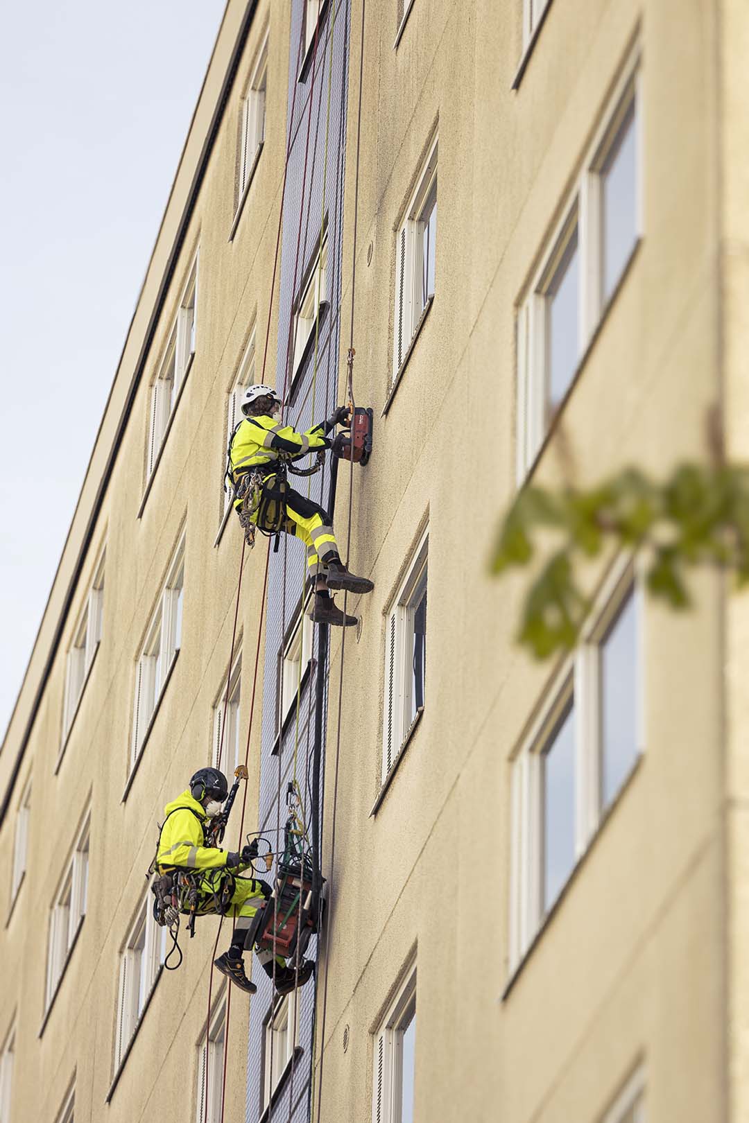 arbeteare hänger på vägg under fasadrenovering